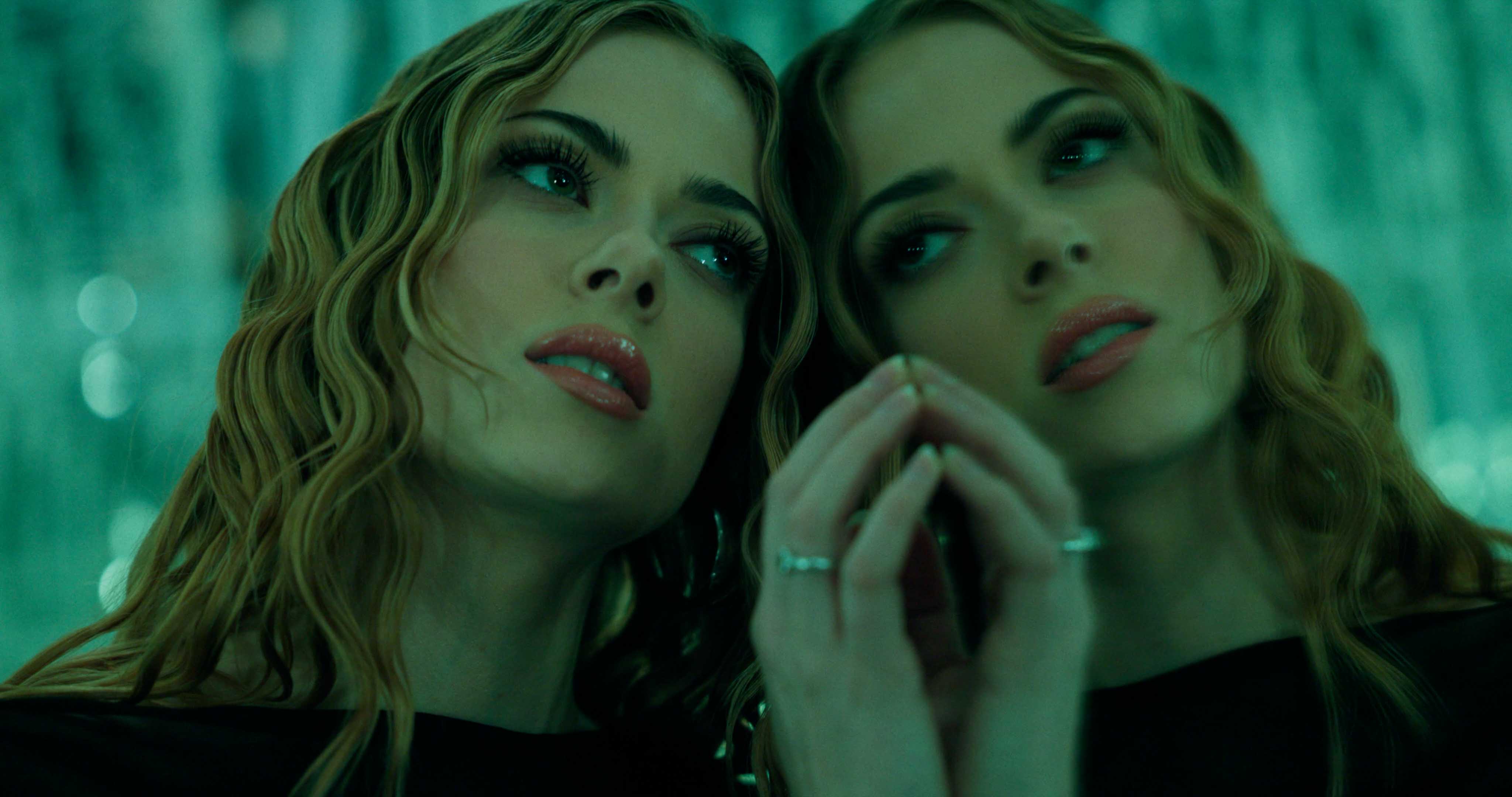 Silhouette of a helmeted racing driver at dusk, mountain skyline faintly visible under violet sky.